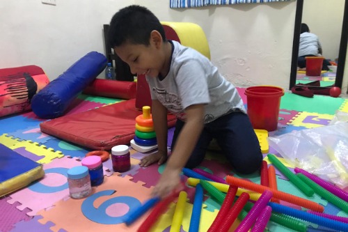 Actividad de motricidad fina con niño y terapeuta